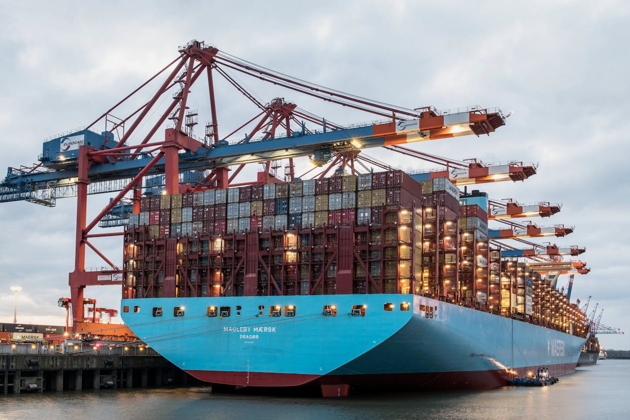 Large container ship at Hamburg port with cranes, showcasing global trade industry.